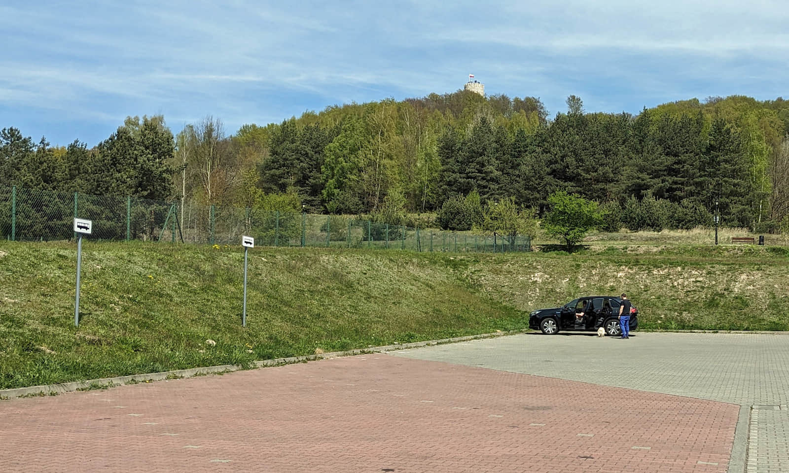 Parking koło szkoły w Babicach - wieża Zamku Lipowiec widoczna ponad lasem