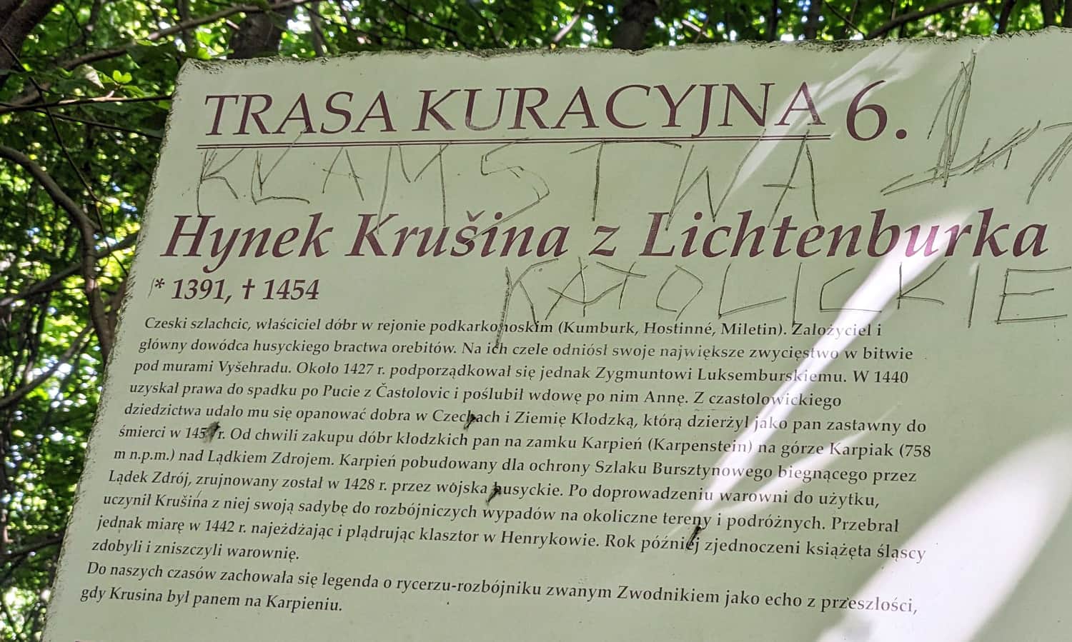 Ruiny Zamku Karpień. Tablica ukryta przy niebieskim szlaku, tuż przed dojściem do ruin od strony Rozdroża Zamkowego