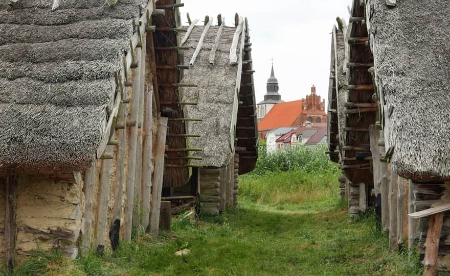 Centrum Słowian i Wikingów, rekonstrukcje chat, w tle kościół św. Mikołaja