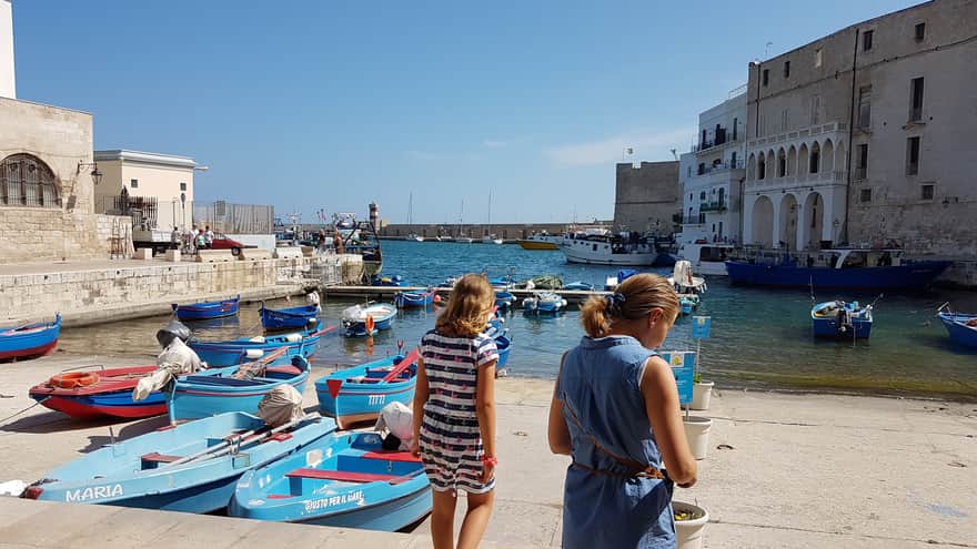The Old Port of Monopoli with blue gozzi and a small lighthouse in the background