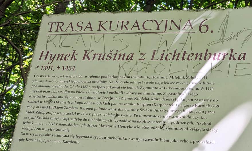 Ruiny Zamku Karpień. Tablica ukryta przy niebieskim szlaku, tuż przed dojściem do ruin od strony Rozdroża Zamkowego